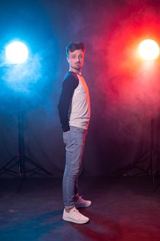Slim young bearded hipster man in casual clothes posing on a red blue background. Concept of style and confidence