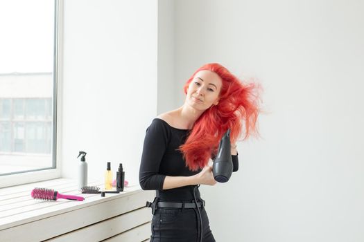 Stylist, fashion, hairdresser, people concept - woman drying her colored hair.