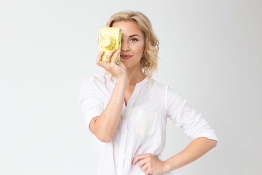 Photographer, hobby and leisure concept - Young blond woman with retro camera on white background with copy space.