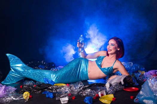 Stupid fairytale mermaid in polluted ocean. Plastic trash and garbage in water. Environmental problem, plastic bag and bottles polluting a coral reef
