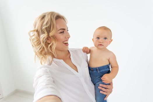 family and motherhood concept - happy young blond mother with little baby taking selfie.