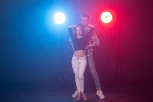 Social dance, bachata, kizomba, zouk, tango concept - Man hugs woman while dancing over lights