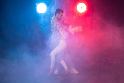 Social dance, bachata, kizomba, zouk, tango concept - Man hugs woman while dancing over lights