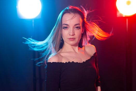 Nightclub, nightlife and people concept - Young woman posing in the dark.