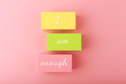 I am enough concept with words written on colorful rectangles against bright pink background. Mental health and self love concept