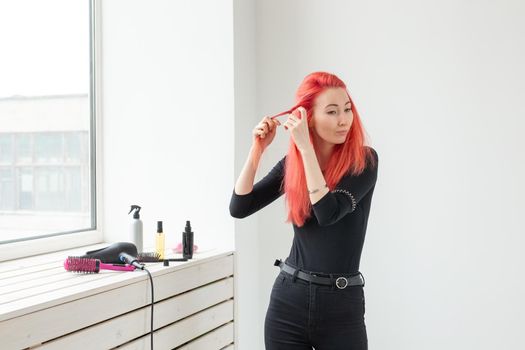 Beautiful red-haired girl with long hair, she is weaves a braid, in a beauty salon. Professional hair care and creating hairstyles