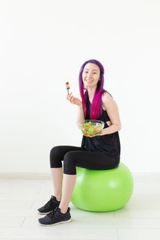 Young unidentified fitness blogger girl holding vegetable salad and measuring tape. Concept of sports lifestyle and proper nutrition