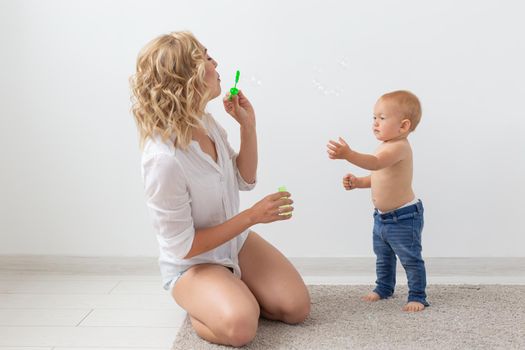 Family and parenting concept - Cute baby playing with her mother on beige carpet.