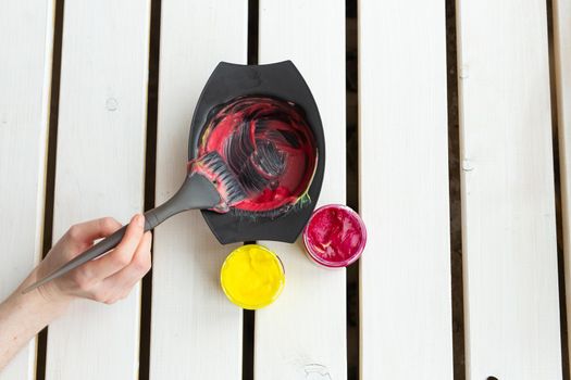 Color and hairdresser concept - female hairdresser in process of mixing hair dye color on the table with white background.