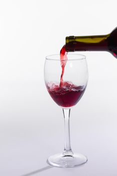 Red wine bottle pour glass on white background.