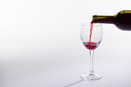 Red wine bottle pour glass on white background.