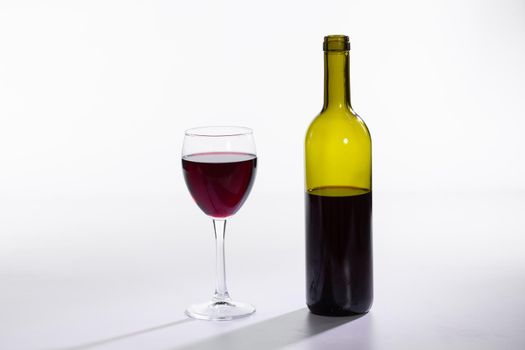 Bottle and glass with red wine on white background.