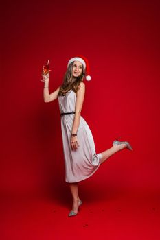 caucasian woman with attractive appearance holds a glass of white wine, picture isolated on red background