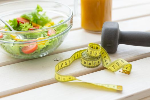 Vegetable salad fruit smoothies and dumbbell lie on a white windowsill. Concept of healthy lifestyle physical activity and proper nutrition