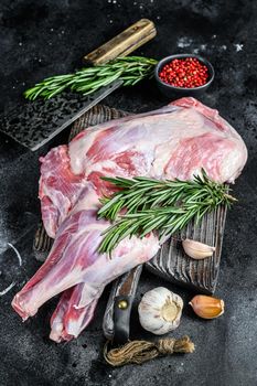 Raw lamb shoulder meat ready for baking with garlic, rosemary. Black background. Top view.