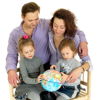 Happy family planning trip around the world. Parents and their little daughters posing with globe against white background. Kids learning about world with help of their parents