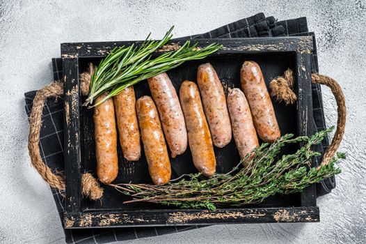 Roasted Bratwurst Hot Dog sausages in a wooden tray with herbs. White background. Top View.