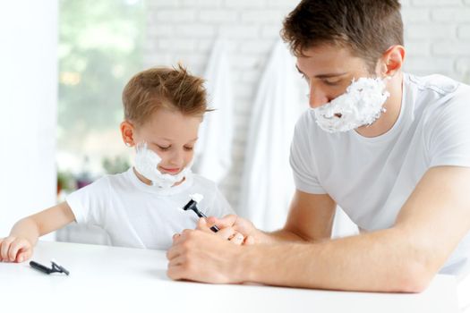 Father and his little son shaving together in bathroom