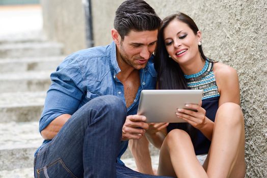 Portrait of beautiful couple with tablet computer in urban background