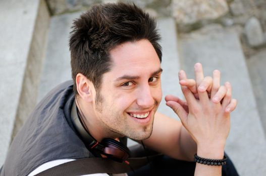 Portrait of young smiling man sitting on steps, with headphones