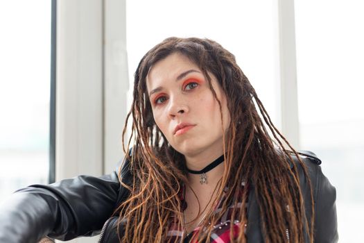 Dreadlocks, hairdresser and style concept - A funny girl with dreadlocks and in leather jacket and fashionable makeup.