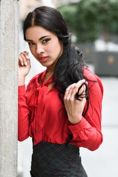 Portrait of hispanic bussinesswoman in urban background wearing red shirt and skirt