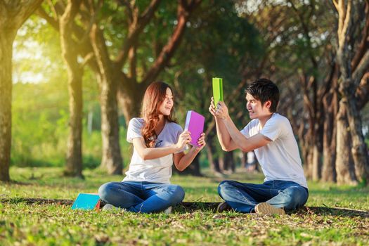 couple holding a book and resting in the park