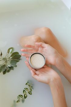Top view of woman hands with solid soap or dry shampoo on white water background, taking bath