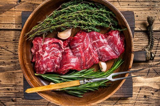 Prime Raw machete skirt beef steak in woode plate with herbs. wooden background. Top view.