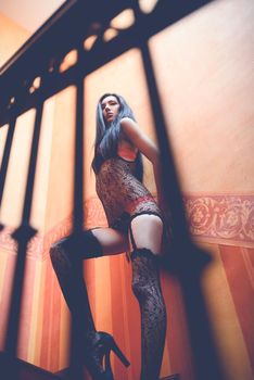 Sexy young woman in lingerie posing near wall. Soft light and colours