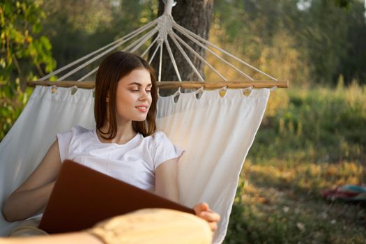 cheerful woman lies in a hammock with a laptop vacation internet travel. High quality photo