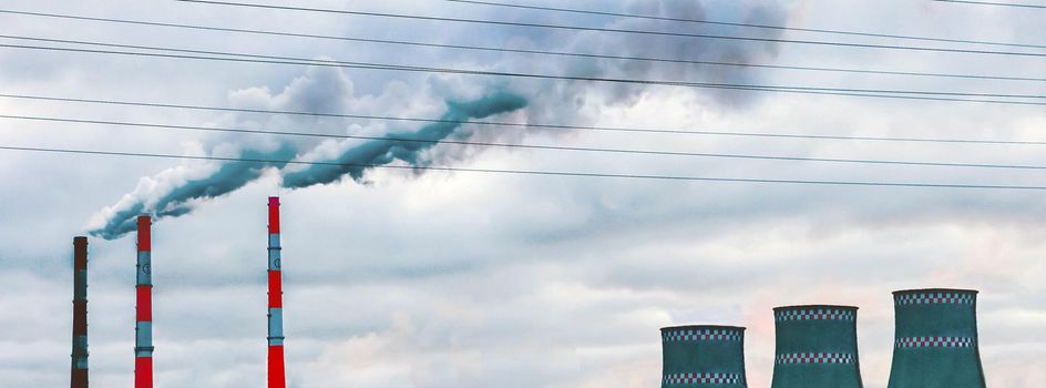 Environmental pollution, environmental problems, smoke from pipes and cooling towers of an industrial enterprise or thermal power plant against the background of a gray cloudy sky.