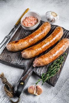 Sausages barbecue fried with spices and herbs on a wooden cutting board. Top view. White background.