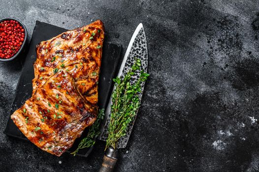 Barbecue pork rack spare ribs on a marble board. Black background. Top view. Copy space.