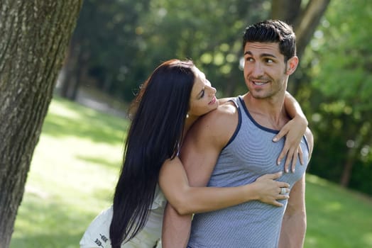 Happy smiling couple laying on green grass in a beautiful park