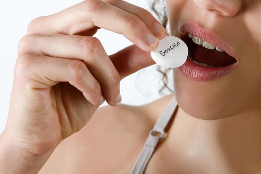 Taking sport pills Close-up of a white pill in woman's fingers.