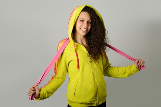Portrait of young cheerful smiling woman in sports wear on urban background