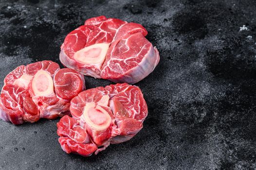 Fresh veal meat osso buco shank steak, italian ossobuco. Black background. Top view. Copy space.