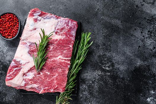 Raw beef short ribs kalbi on marble board. Black background. Top view. Copy space.