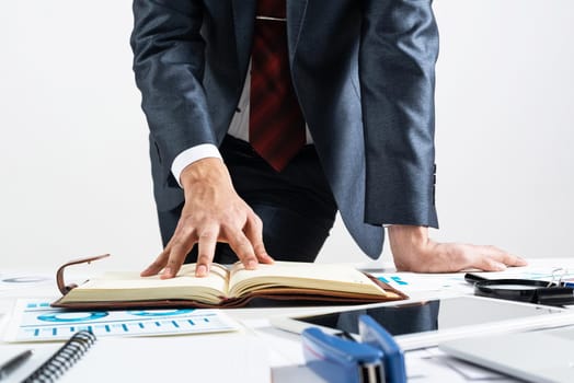 Businessman analyzing financial documents at office desk. Financial expertise and consulting. Manager in suit and tie planning day with personal organizer. Time management and work organization.
