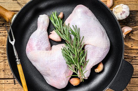 Raw chicken legs in a pan ready for the Grill. wooden background. Top view.