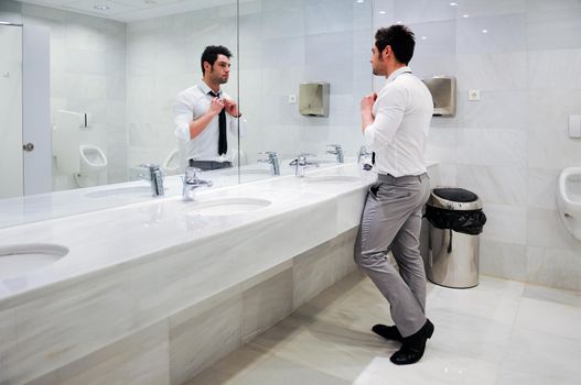 Man getting dressed in a public restroom with mirror