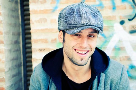 Portrait of handsome man in urban background wearing a retro cap