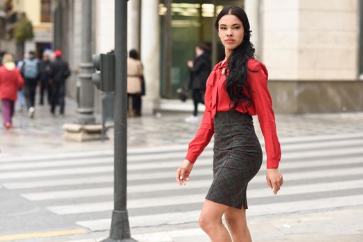 Portrait of hispanic bussinesswoman in urban background wearing red shirt and skirt