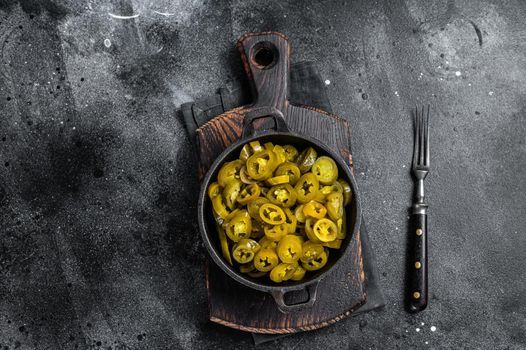 Pickled Green Sliced Jalapenos in a pan. Black background. Top view.