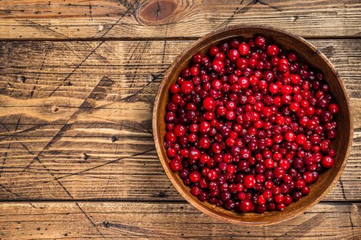 Red Cranberry berry in a wooden plate. Wooden background. Top view. Copy space.