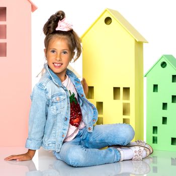 A cute little girl is playing with wooden houses. The concept of family happiness, play, creative development of the child.