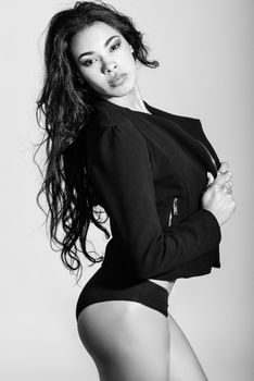 Portrait of hispanic woman wearing black jacket and panties on white background. Studio shot