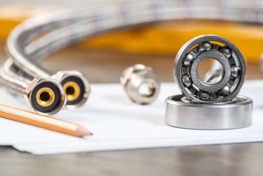 Plumbing pipeline and ball bearings laying on table. Water fittings and connections with segments of braided hose. Steel details for engine mechanisms. House infrastructure designing and installation