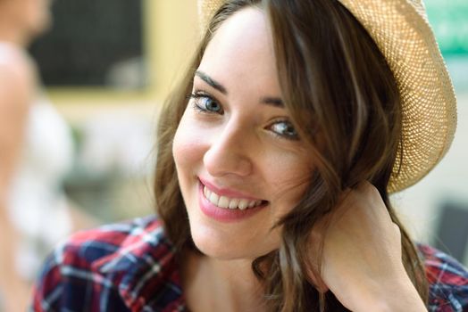 Close-up portrait of young woman with beautiful blue eyes wearing plaid shirt and sun hat
